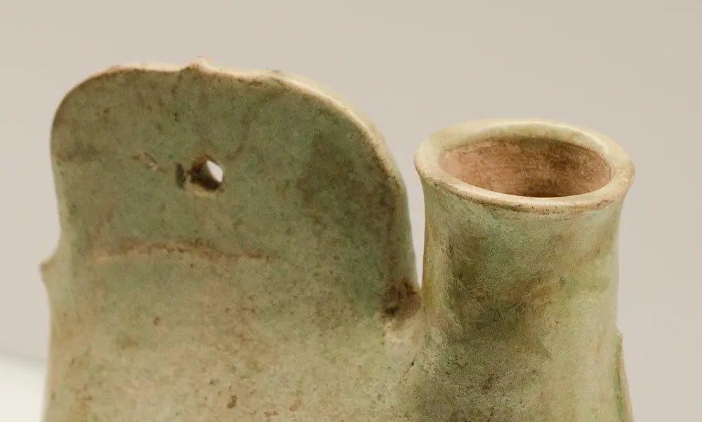 Macro shot of the unglazed spout interior and drilled suspension hole on a Liao green glaze cockscomb flask